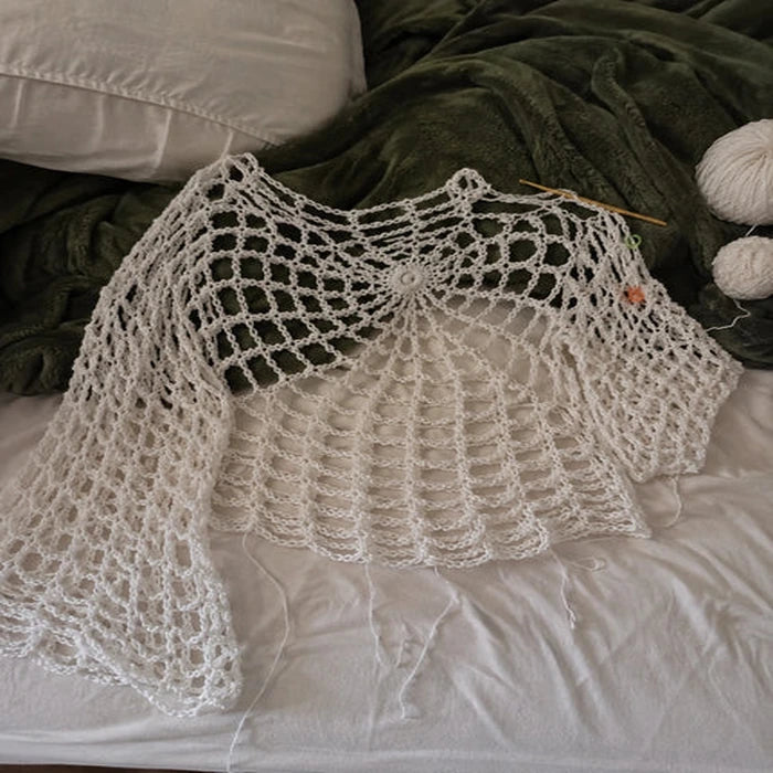 Customer work-in-progress photo of the webbed crochet top on a bed