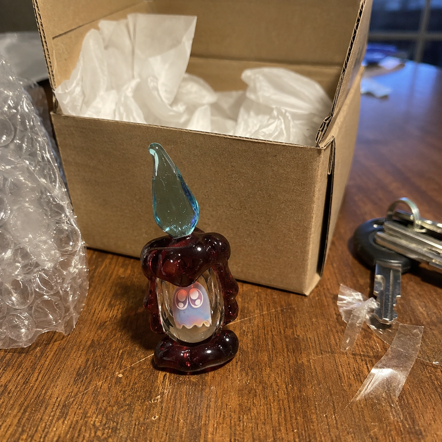 Glass ghost collectible beside its shipping box