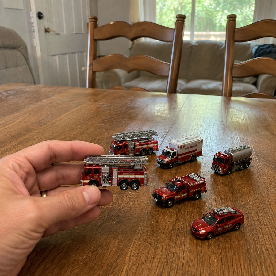 Miniature ladder fire truck held in an adult hand for scale