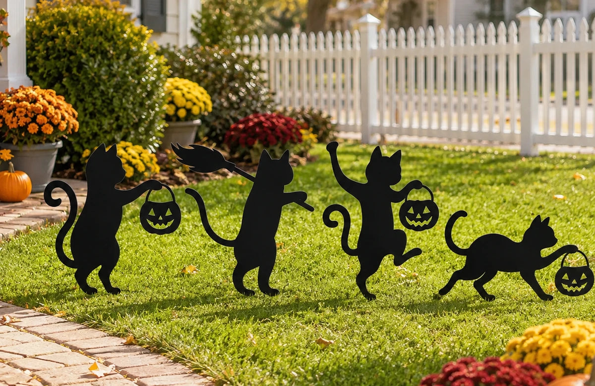 Four black cat garden stakes displayed together beside a walkway