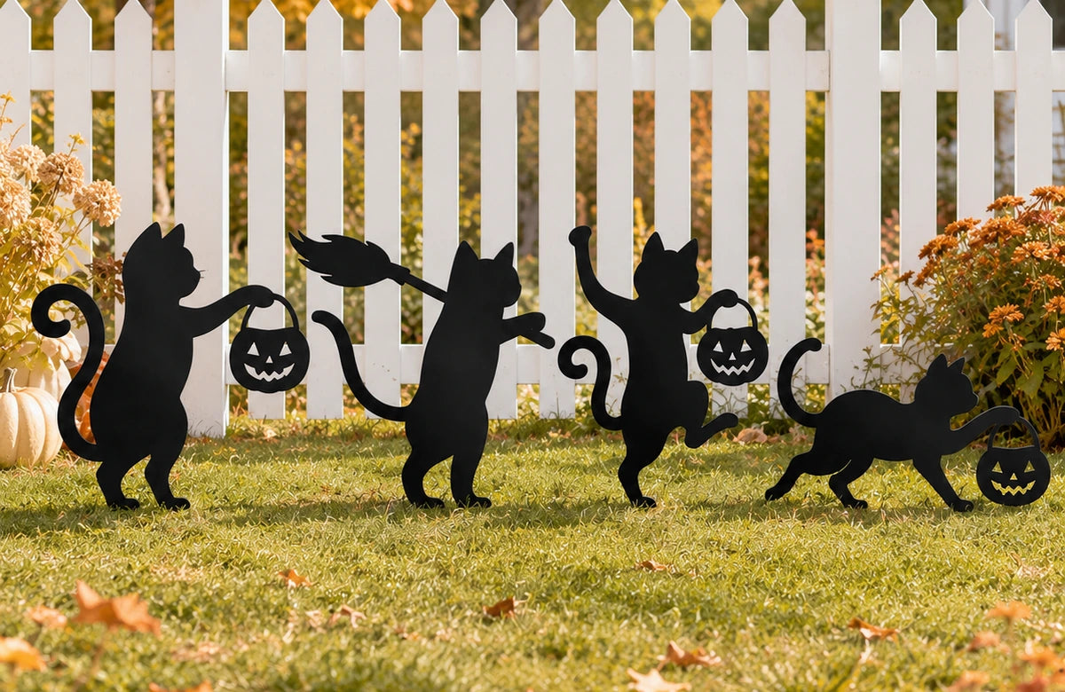 Black cat garden stakes displayed in an autumn yard by a white fence