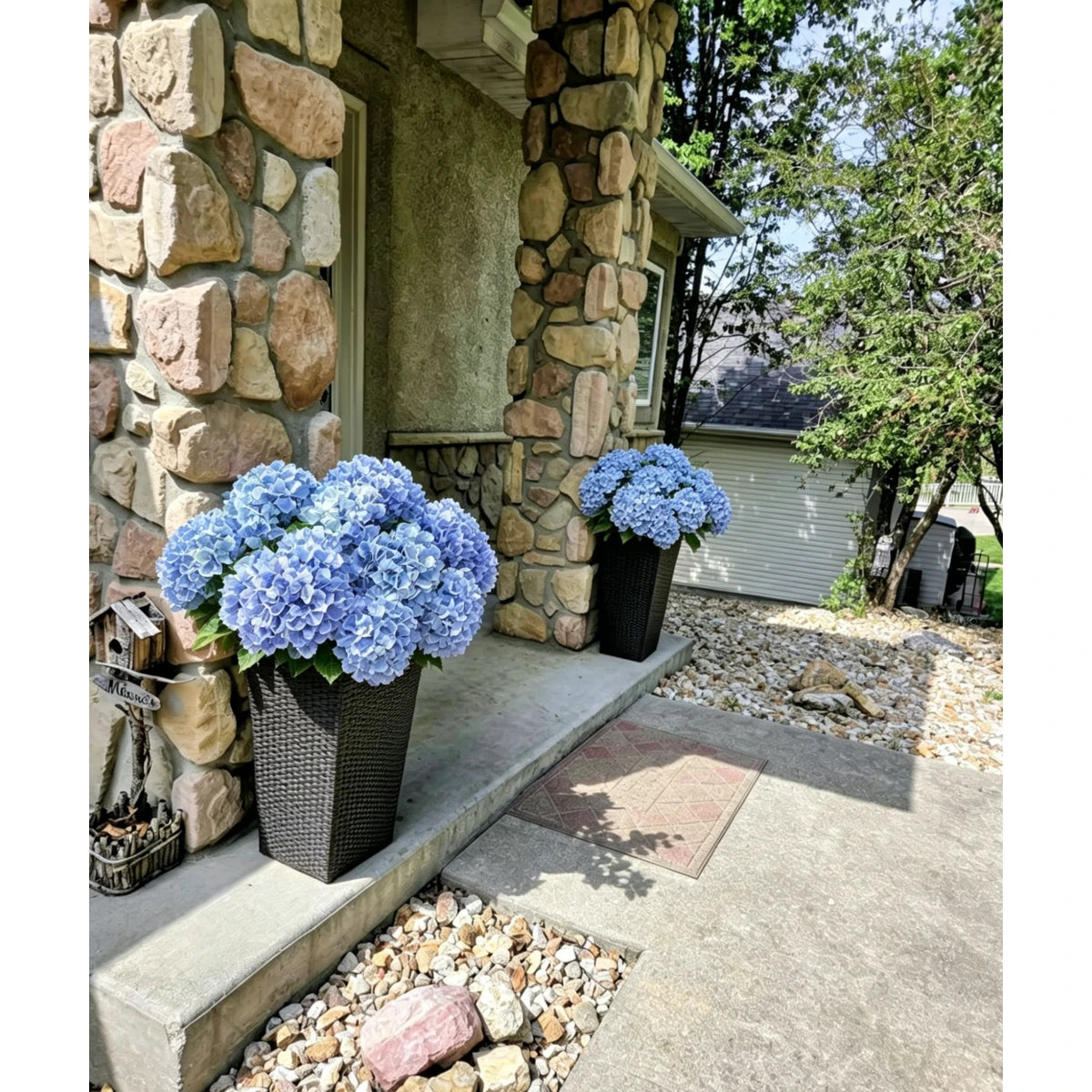 Outdoor blue artificial hydrangea flowers by a stone porch