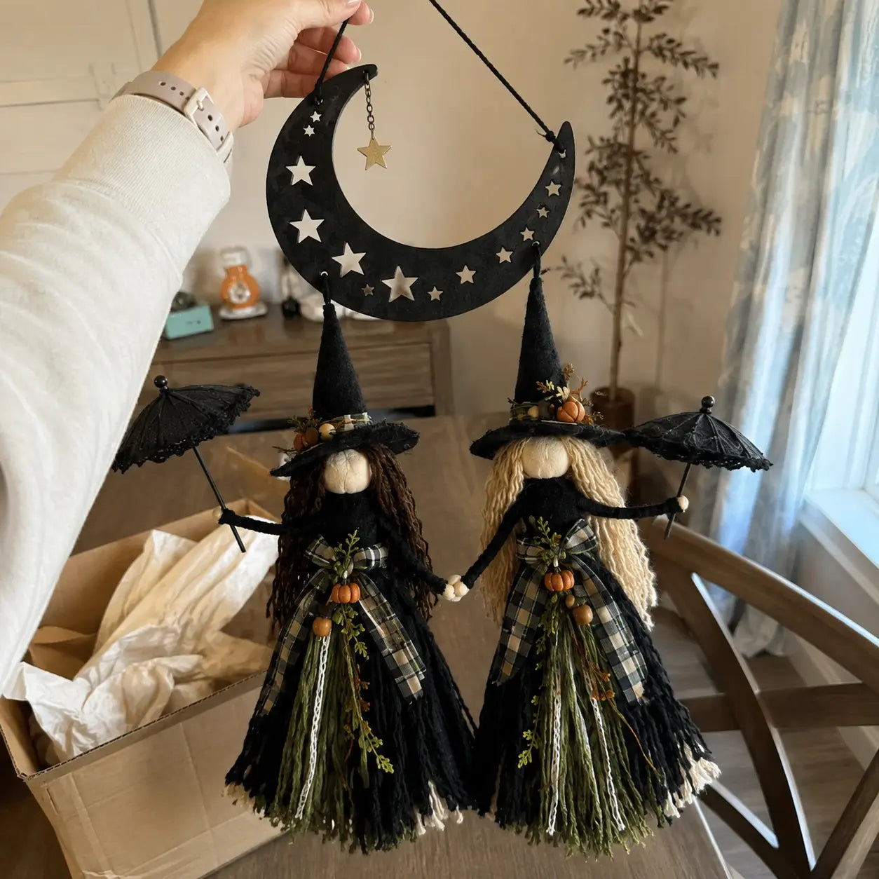 Customer holding the Moonlit Witch Sisters wall hanging after unboxing