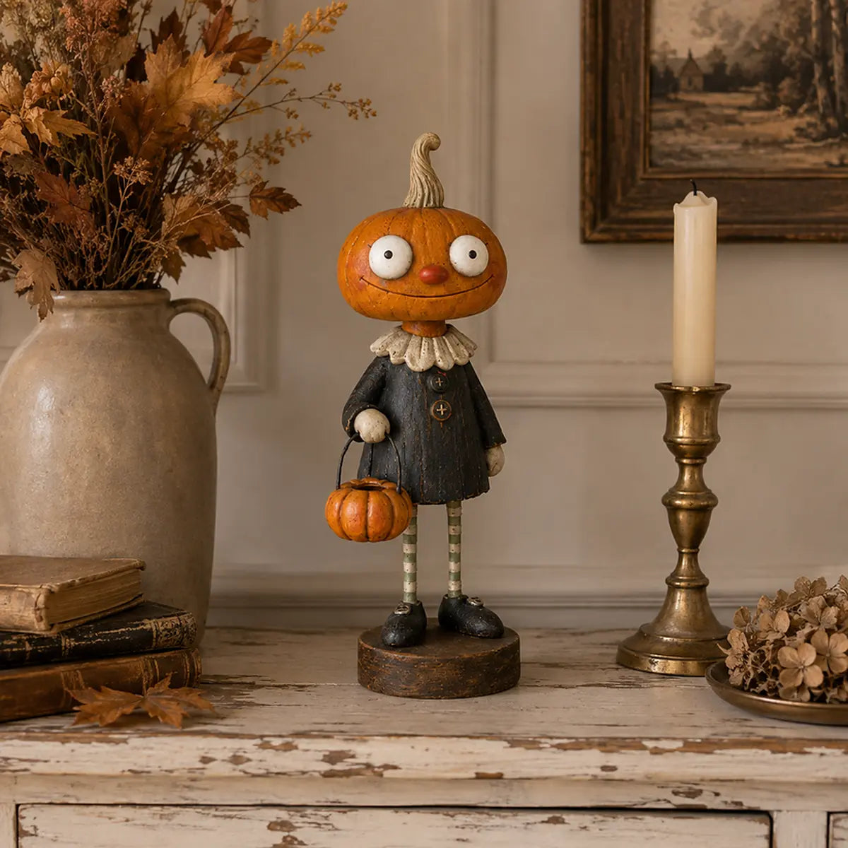 Pumpkin Boy figurine beside vintage books and a brass candleholder